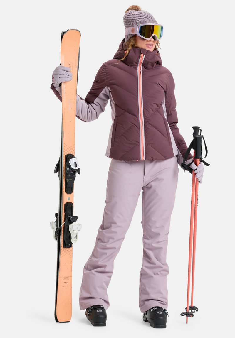 Skiausrüstung in verschiedenen Lila-Tönen; isolierte Jacke mit Reißverschluss, passende Hose, Handschuhe, Mütze, Skibrille, Skistöcke und orangefarbene Skier.