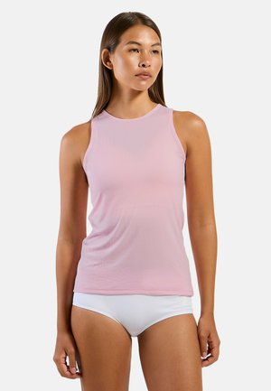 Woman with straight brown hair wearing a light pink sleeveless ribbed top and white high-cut briefs, standing against a plain background.