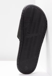 Black Nike slide sandal featuring a textured rubber sole with a herringbone pattern, smooth upper, and logo on the side.