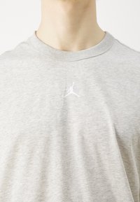 Gray cotton T-shirt with short sleeves, crew neck, and a small white Jumpman logo on the chest. Soft texture with a classic fit.