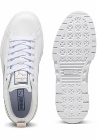 White sneakers made of synthetic leather featuring a padded collar, lace closure, and textured rubber outsole with a patterned tread.