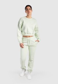 Ljusgrön bomullströja med en cropped design och broderad logotyp, tillsammans med matchande sweatpants med elastisk midja.