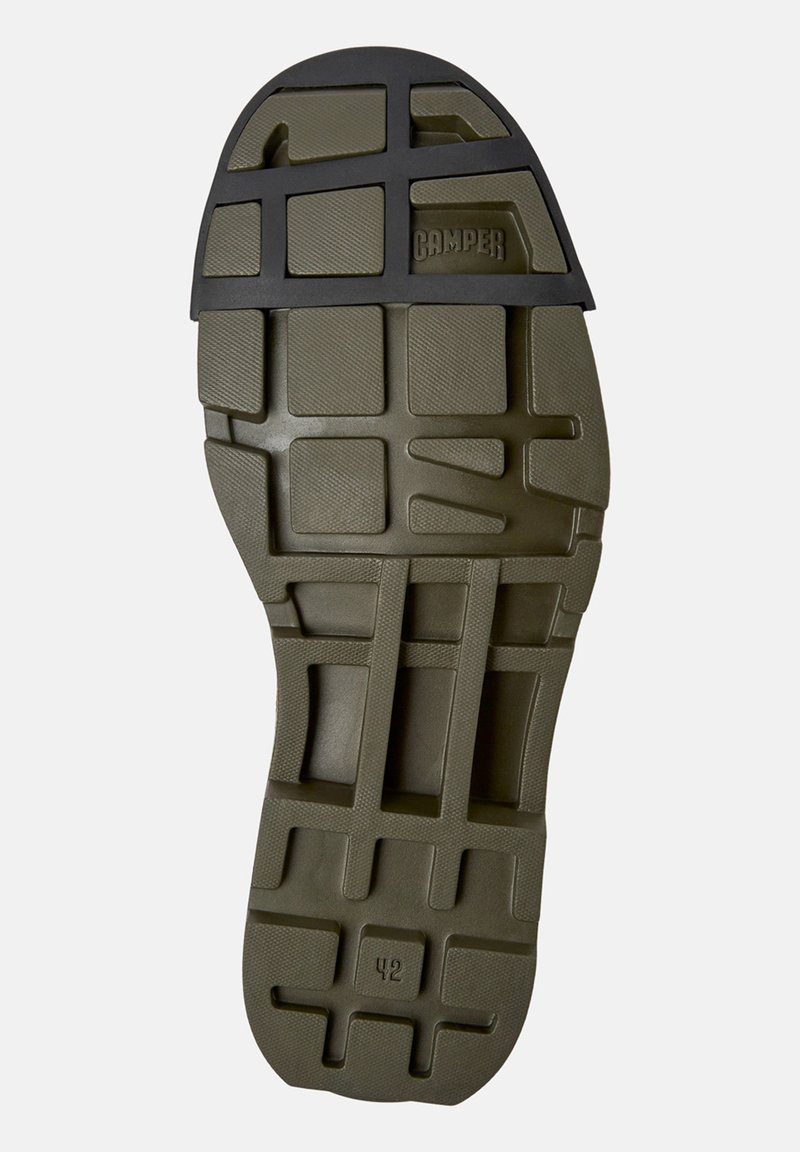 Olivgrüne Gummischuhsohle mit strukturiertem Oberflächen, die ein Rautenmuster und rechteckige Ausschnitte aufweist. Größe gekennzeichnet als 42.