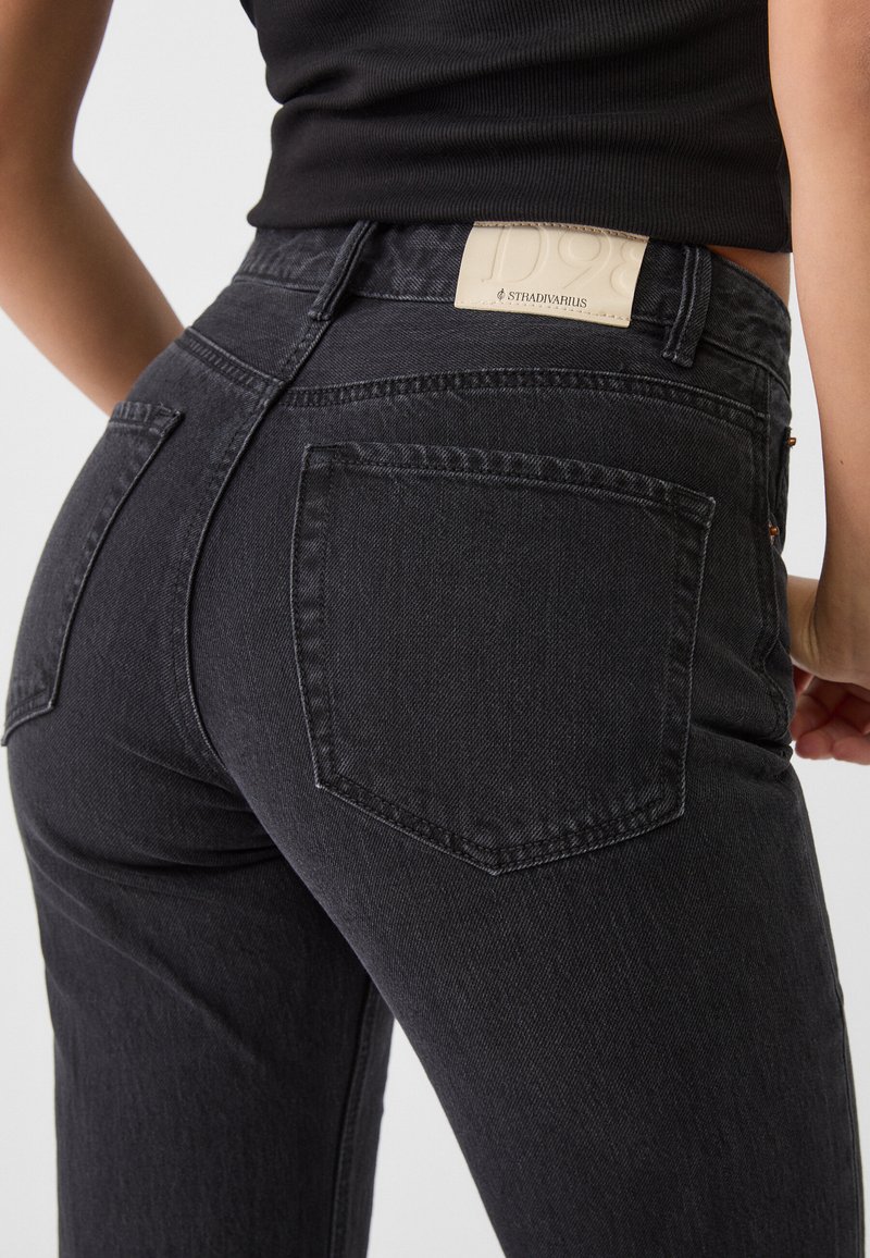 Jean noir taille haute en denim, comportant deux poches arrière et une étiquette en cuir estampillée sur la ceinture. Design texturé et ajusté.