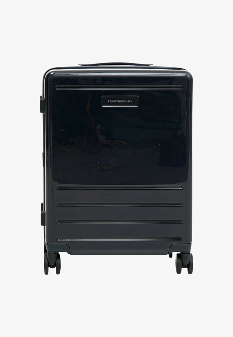Valigia rigida nera con scanalature orizzontali, maniglia superiore, due maniglie laterali e quattro ruote. Presenta un logo del marchio sul fronte.