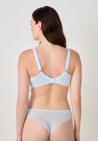 Soutien-gorge en dentelle bleu clair avec des bretelles réglables et une fermeture à crochets, associé à une culotte en dentelle assortie, mettant en avant des bords festonnés et des motifs complexes.