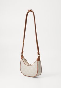 Bolso de hombro de lona beige con detalles en cuero marrón, diseño curvado, patrón de logo decorativo y un cierre con cremallera en un lado.