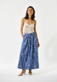 Mėlynas raštuotas maxi sijonas su gėlių ir paisley dizainais, derinamas su kremine šilko topu. Sijonas turi aukštą liemenį ir kišenes.