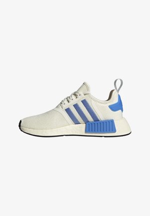 Baskets de sport blanches avec des bandes bleues, des blocs de support de semelle bleus, des lacets blancs et une languette grise au talon.