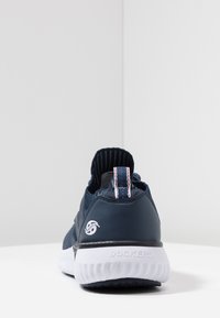 Scarpa sportiva blu navy con tomaia in rete, colletto imbottito e suola bianca. Presenta un logo sul tallone e un'accenno a righe nel nastro di estrazione.