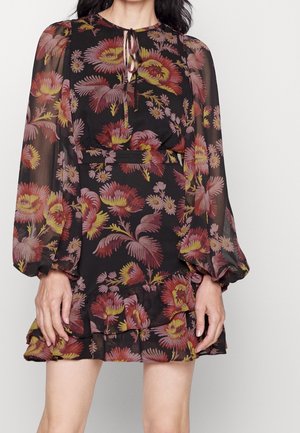 Zwarte bloemenjurk met lange, opgerolde mouwen; heeft roze en gele bloemmotieven. De rok heeft gelaagde volants en een sleutelgat halslijn.