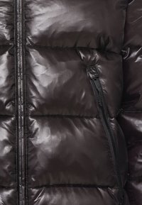 Czarna kurtka puchowa o błyszczącej, pikowanej strukturze. Posiada zamek błyskawiczny z przodu oraz boczną kieszeń z ukrytym zamkiem, zapewniającą bezpieczne przechowywanie.