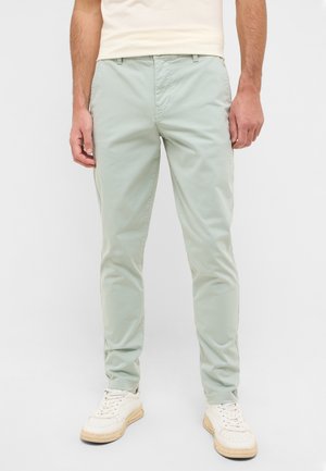 Light green, slim-fit trousers made of lightweight fabric. Features front pockets and a smooth texture. Worn with white athletic shoes.