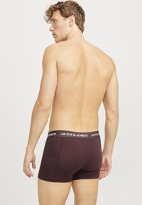 Burgundy boxer briefs with a black elastic waistband featuring white "JACK & JONES" branding. Smooth fabric, fitted design.