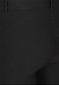 Zwarte leggings met een gladde textuur, hoge taille en geen zichtbare patronen of accenten. De zijkanten zijn minimaal, wat zorgt voor een strakke uitstraling.