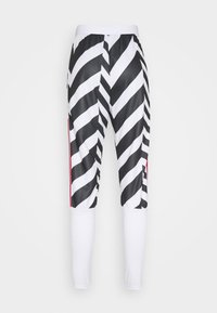 Tajta leggings med svarta och vita diagonala ränder på övre delen av benen och solid vit tyg från knäna och nedåt.