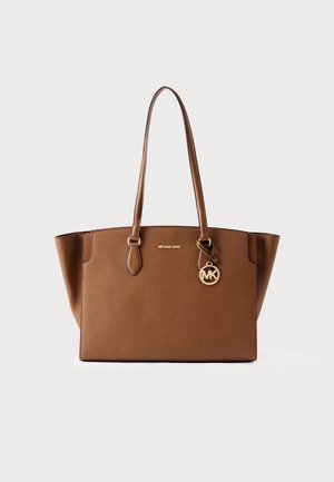 Bruine leren shopper met dubbele handvatten, gouden accenten en een hangende MK-logo. Heeft een gestructureerde vorm en een gladde textuur.