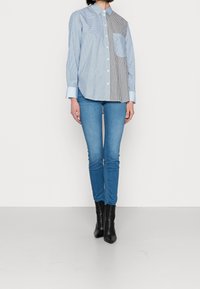 Blå och vit randig skjorta med knappar och en bröstficka på vänster sida, tillsammans med slim fit blå jeans och svarta ankelstövlar.