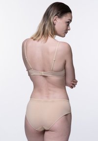 Brezšivni komplet spodnjega perila v kožni barvi z nastavljivimi trakovi, mehko teksturo in preprostim dizajnom. Ima zaponko na hrbtni strani.