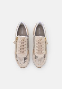 Baskets beiges avec un motif texturé de peau de serpent sur les côtés, lacets plats et un accent de fermeture éclair latérale. Matériau doux et doublure blanche contrastante.