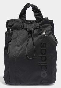 Black nylon drawstring bag with a gathered top, featuring a glossy black adidas logo and a removable logo tag. Smooth texture.