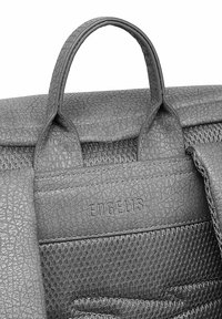 Šedá kabelka s texturovaným koženým povrchem, obsahující síťovaný panel, dvojité držadla a ražené logo na přední kapse.