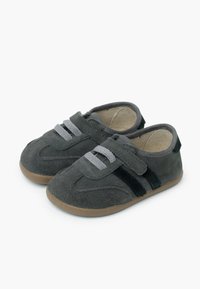 Scarpe per bambini di colore grigio scuro con lacci grigio chiaro, strisce laterali nere, cinturini in velcro e suole in gomma marrone chiaro su sfondo bianco.
