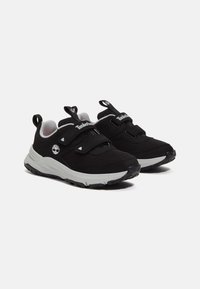 Baskets de sport noires en matériau en mesh, munies de deux sangles Velcro, avec des accents gris et une semelle en caoutchouc texturé pour l'adhérence.