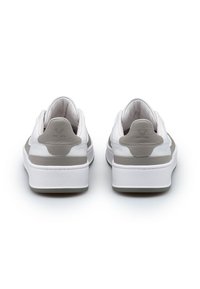 Paio di sneaker bianche con dettagli grigi viste dal retro su uno sfondo bianco, con una suola spessa e un tab retro testurizzato.