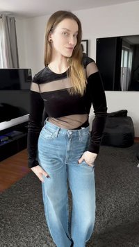 Black velvet long-sleeve top with sheer mesh panels paired with high-waisted light blue wide-leg jeans. Smooth texture, relaxed fit.