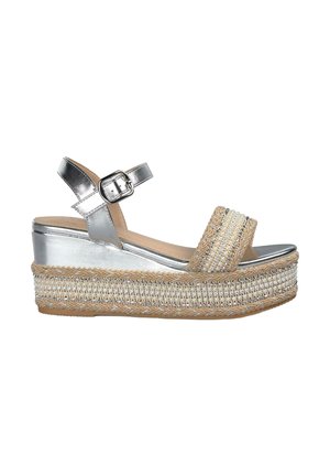 Zilveren platform sandaal met een geweven beige band. Voorzien van een gestructureerde decoratieve band en een verstelbare enkelriem. Jute-stijl loopzool.