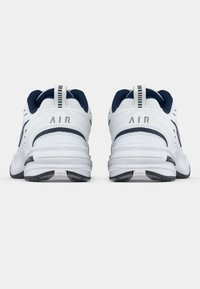 Tenis desportivos brancos e azul-marinho com um cabedal em couro suave, sola acolchoada e a marca "AIR" no calcanhar e na língua.