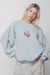 Hellblaues, oversized Sweatshirt aus weichem Material, das ein Clown-Design mit einer Schüssel Ramen und einem kleinen Logo an der Seite zeigt.