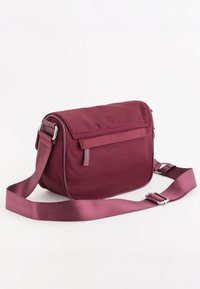 Bordeaux messenger taske lavet af et glat, vandafvisende stof, med en lynlås lomme, justerbar rem og rektangulær form. Udstyret med sølvdetaljer.