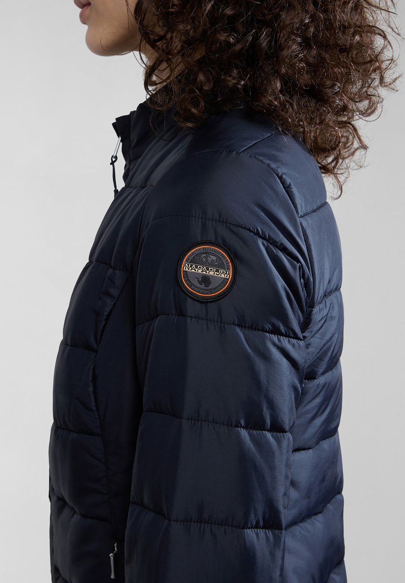 Granatowa kurtka puchowa z pikowanym wzorem i okrągłą naszywką z logo na rękawie. Posiada zamek błyskawiczny i regulowany kołnierz.