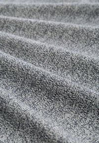 Țesătură textilă gri texturată cu un model subtil; pliată cu adâncimi variate, evidențiind fibre textile moi și o suprafață netedă.