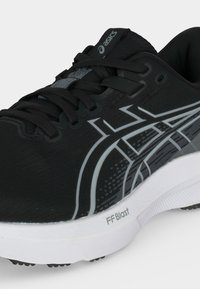 Μαύρο και γκρι παπούτσι τρεξίματος Asics με λευκή σόλα, με την ετικέτα FF Blast και μαύρα κορδόνια, που δείχνει πλάγια και μπροστινή όψη.