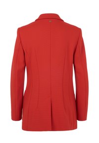 Roter Blazer mit strukturierter Struktur, betonten Schultern, Reverskragen und Rückenschlitz für mehr Bewegungsfreiheit. Enthält goldene Beschläge am Kragen.