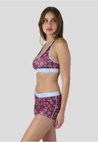 Bordeauxrotes Sport-BH- und Shorts-Set mit floralem Muster, hellblauen elastischen Bändern, weichem Stoff, Racerback-Design, figurbetonter Form und kontrastierenden Details.
