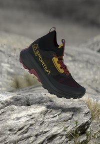 Trailrunning-sko gjord av svart textil och gummi. Har röda och gula accenter, en hög krage och en texturerad sula för grepp.