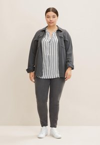 Chaqueta de denim gris sobre una blusa a rayas gris y blanca, combinada con jeans grises y zapatillas blancas. Textura suave, corte relajado.