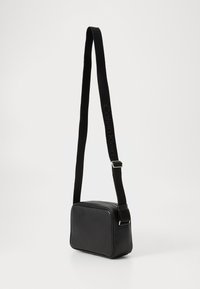 Black leather rectangular crossbody bag with long adjustable strap featuring subtle Calvin Klein logo.