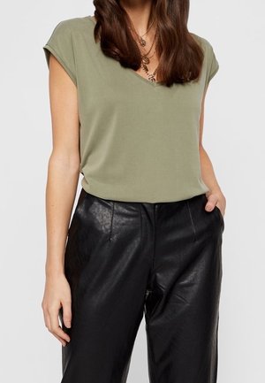 Haut vert olive à manches courtes avec un design en V, associé à un pantalon en cuir noir taille haute avec une texture lisse et une coupe ajustée.