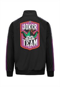 Giacca nera con un grande logo colorato "Joker Team F.C." sulla schiena, con accenti verdi e viola e dettagli a righe sulle maniche.