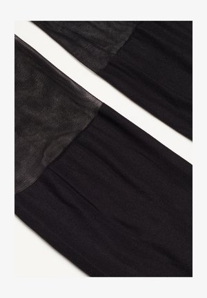 Czarne jedwabne pończochy z półprzezroczystą górną częścią, charakteryzujące się gładką teksturą i subtelnym blaskiem, przechodzące w nieprzezroczystą dolną część.