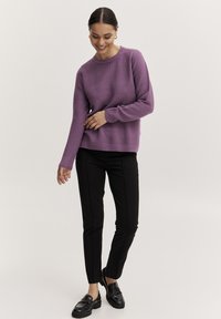 Lila strukturerad stickad tröja med rund halsringning, i kombination med svarta figursydda byxor och svarta loafers för en strömlinjeformad look.