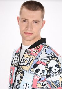 Colorful bomber jacket featuring a comic-style panda print on a light background, zip closure, and a black ribbed collar.
