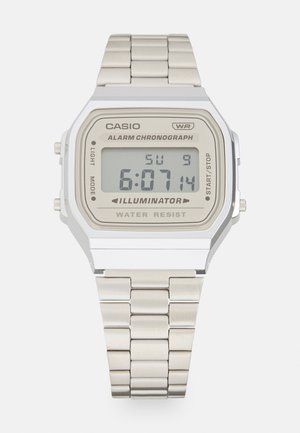 Relógio digital Casio com caixa retangular em aço inoxidável prateado, mostrador bege, visor preto, bracelete de elos metálicos e características de resistência à água.