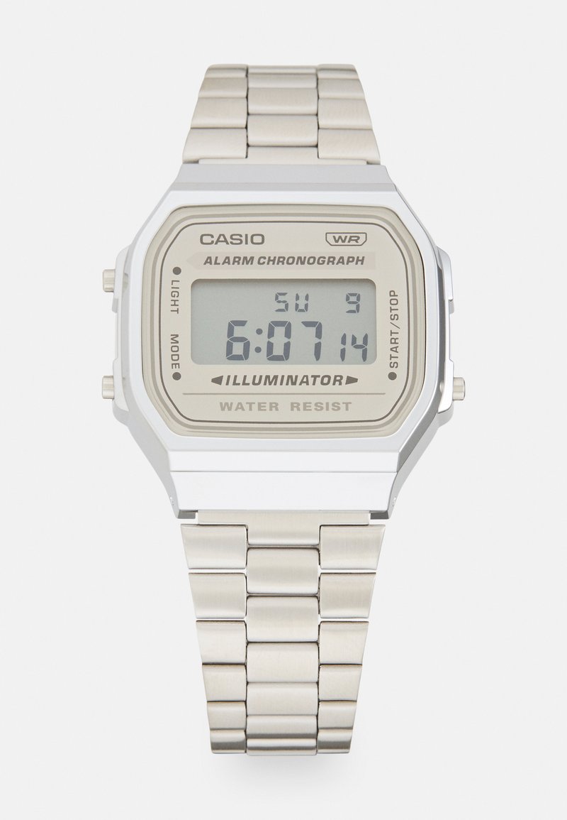 Digitální hodinky Casio s obdélníkovým pouzdrem ze stříbrné nerezové oceli, béžovým ciferníkem, černým displejem, kovovým řetízkem a voděodolnými vlastnostmi.
