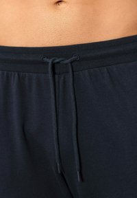 Dunkelblaue Sporthosen mit einem Kordelzugbund, ausgestattet mit einer glatten Textur und einem gerippten Bund. Die Hosen sind lässig und bequem.